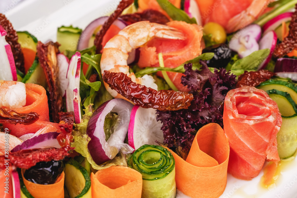 Mediterranean snack. Sliced ​​radishes, tomatoes, fried shrimps, salmon, onion rings, chili peppers and greens