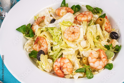 Mediterranean salad. Cabbage, tomatoes, shrimps, olives, olives, basil and rosemary, seasoned with olive oil