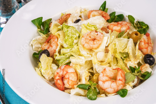 Mediterranean salad. Cabbage, tomatoes, shrimps, olives, olives, basil and rosemary, seasoned with olive oil