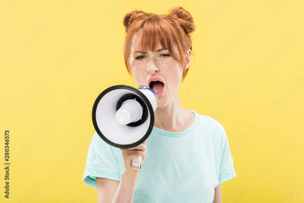angry redhead young woman holding megaphone and screaming isolated on yellow angry redhead young woman holding megaphone and screaming isolated on yellow