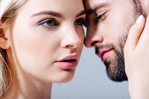 beautiful blonde young woman embracing man isolated on grey