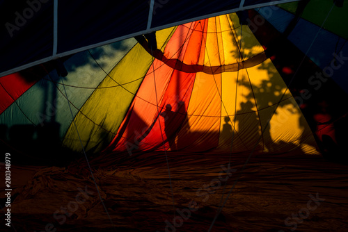Colourful silhouettes of people playing close to hot air balloons. Creative backgrounds and rainbow colours with fire flares and shadows. Beautiful textures in summer light. Adventure and chill summer