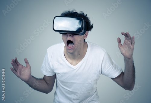Young man having a scary experience with Virtual Reality goggles shouting in shock