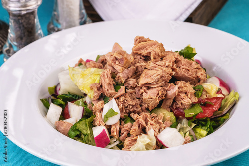  Seafood, Mediterranean cuisine. Salad from sea tuna fish with greens, cucumber, lemon and chili pepper, radish. Japanese food