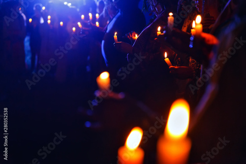 Many people in a crowd holding lit candles at night