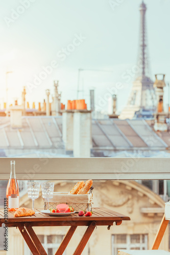 Paris luxury lifestyle. Pink wine, two glasses, traditional french bakery products and strawberries on a balcony. Toned image in vintage colors