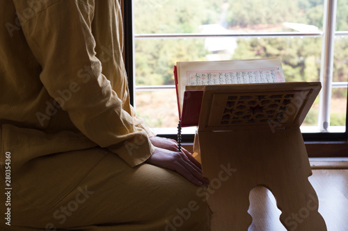 Quran and rosary beads on the wooden background with candle for Islamic concept. Holy book Koran for Muslims holiday, Ramadan,blessed Friday message