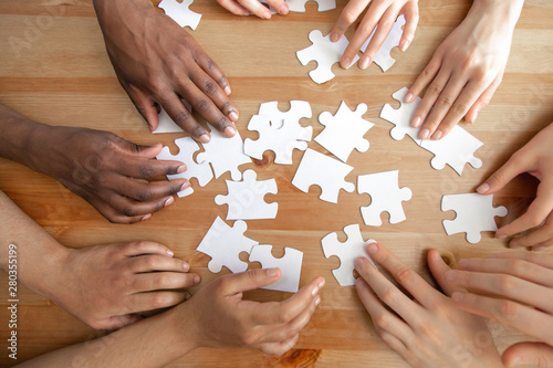 Принти на полотні Close up top above view diverse hands assembling puzzles.