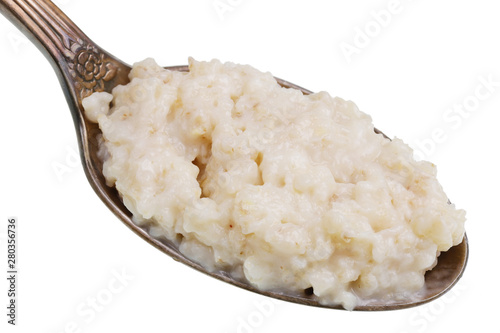 In the old golden spoon there is a small pile of food - oatmeal with milk  isolated macro