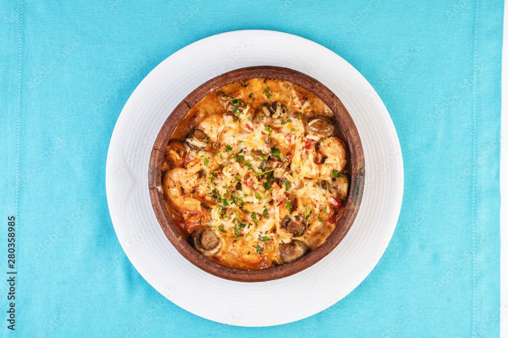 Mediterranean dish, European cuisine. Seafood stew soup- shrimp, fish meat and mushrooms, with cheese and greens