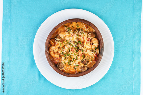 Mediterranean dish, European cuisine. Seafood stew soup- shrimp, fish meat and mushrooms, with cheese and greens