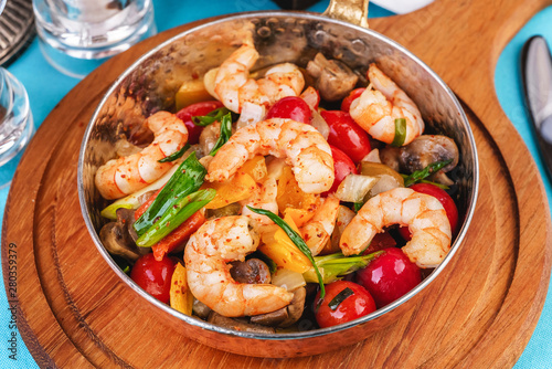 Seafood, Mediterranean cuisine, European dish. Warm salad of grilled fish pieces, shrimps and mussels in a frying pan, with grilled vegetables - with green onions, greens, mushrooms and vegetables.