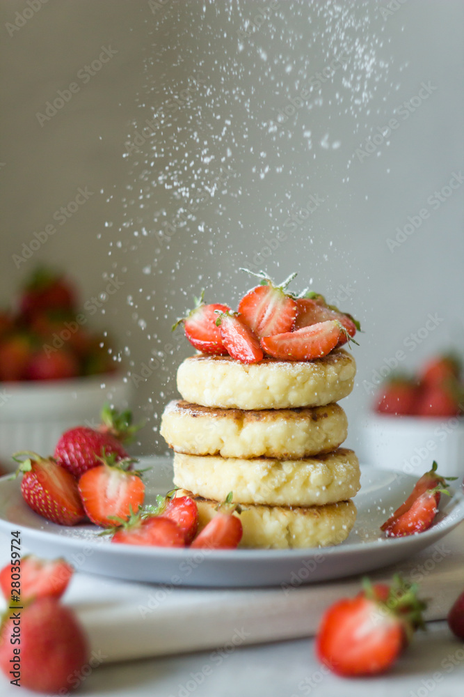 Cottage cheese pancakes syrniki with strawberrys. Powdered sugar pours. Delicious healthy summer Breakfast. Copy space, side view.