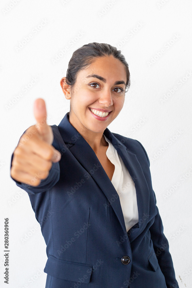 Happy businesswoman showing thumb up. Beautiful cheerful young woman showing thumb up and smiling at camera isolated on grey background. Gesture concept Happy businesswoman showing thumb up. Beautiful cheerful young woman showing thumb up and smiling at camera isolated on grey background. Gesture concept
