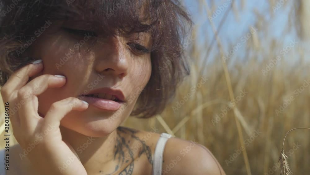 Close-up portrait of cute woman with short hair on the wheat field. Girl enjoys nature. Confident carefree girl outdoors. Real people series. Close-up portrait of cute woman with short hair on the wheat field. Girl enjoys nature. Confident carefree girl outdoors. Real people series.
