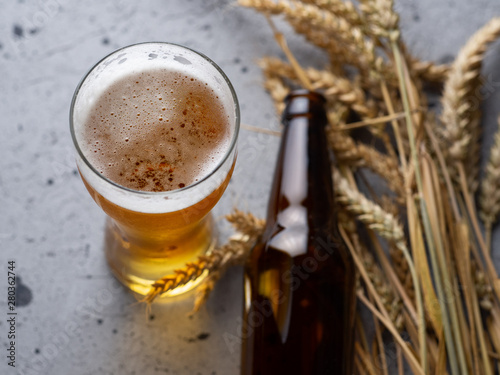 A glass of beer and a beer bottle on the grey stone table top view . Wheat beer photo