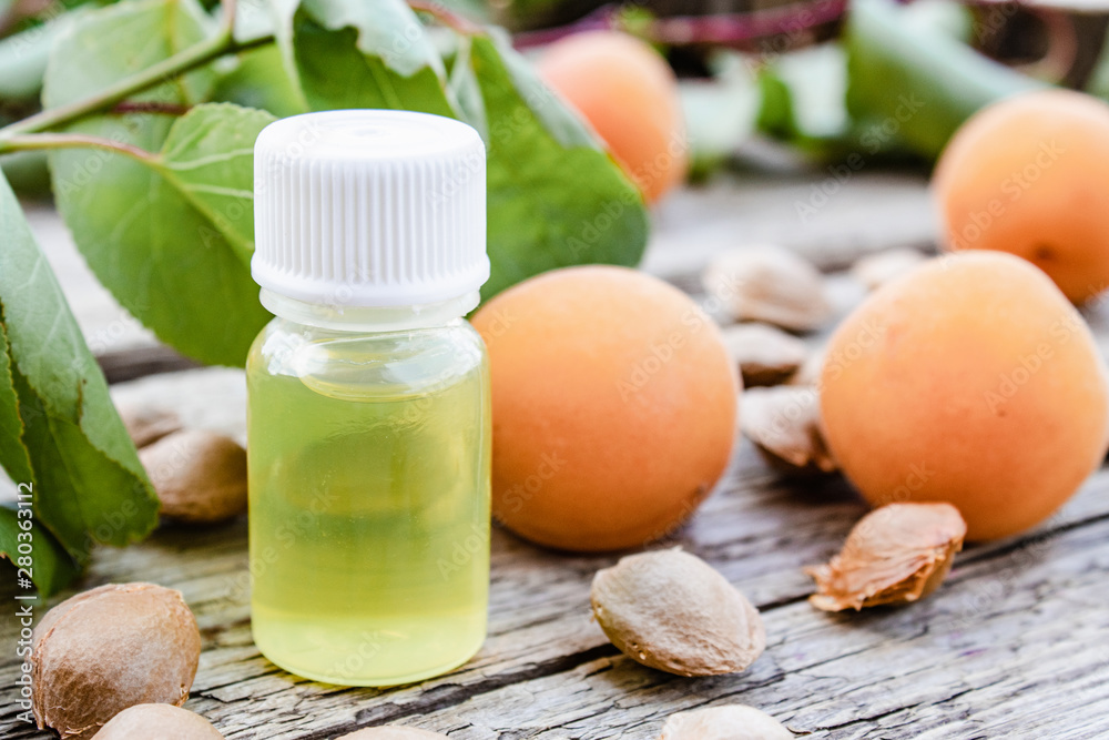Apricot flavor oil and fresh apricots on a wooden table. Apricot flavor oil and fresh apricots on a wooden table.
