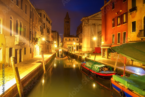 Venice at night, Italy. Beautiful view on narrow venetian canal with boats at night. Venezia illuminated by citylights