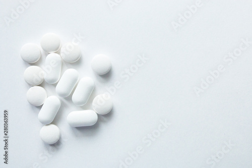 White capsules isolated on white background  copyspace for text  selective focus  top view. Pain meds  health  pills for the treatment of the concept of drug abuse