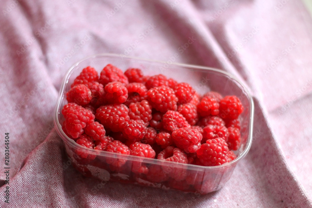 Fresh raspberries in a container. Selective focus, pink background. Fresh raspberries in a container. Selective focus, pink background.