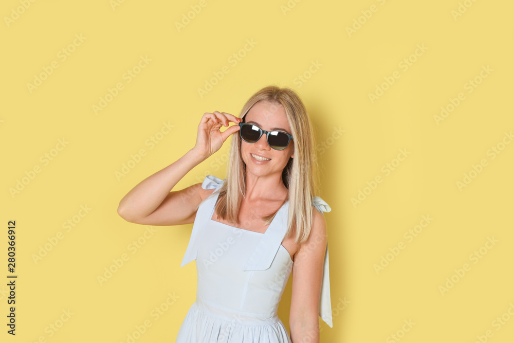 Blonde woman in sunglasses on yellow background