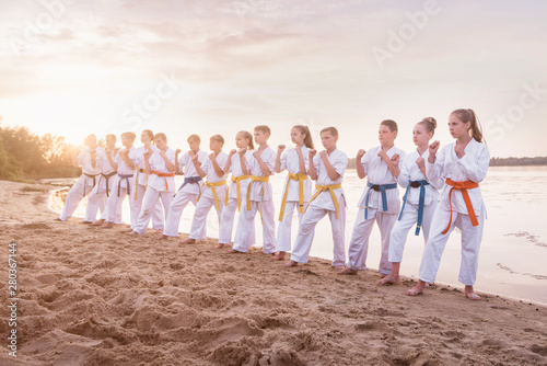 group of kids training karate martial arts on sunset beach photo