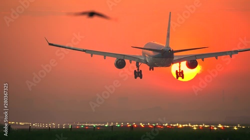 Airplane crossing the sun at sunrise photo