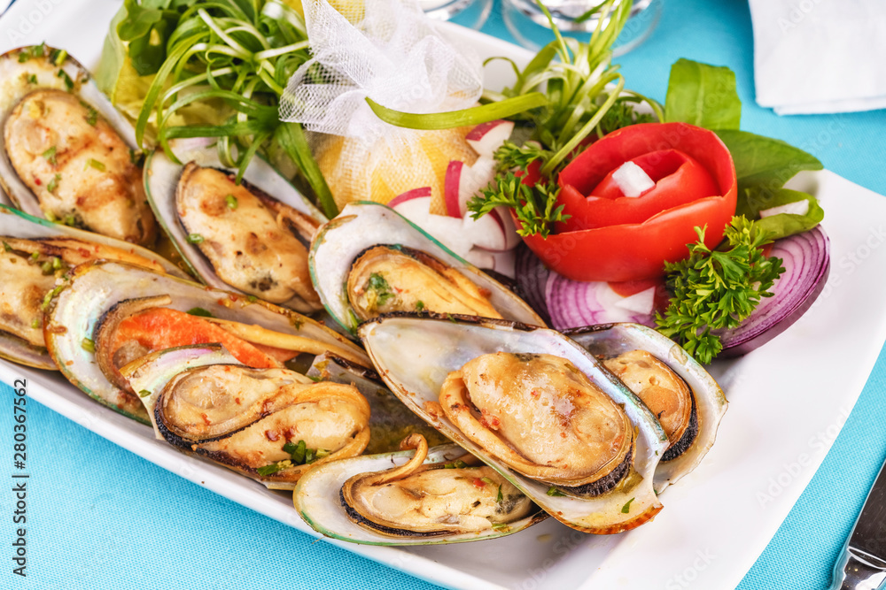 European cuisine, Mediterranean dish. Plate of assorted mussels and oysters cooked with spices, onions, herbs, tomatoarmi and lemons European cuisine, Mediterranean dish. Plate of assorted mussels and oysters cooked with spices, onions, herbs, tomatoarmi and lemons