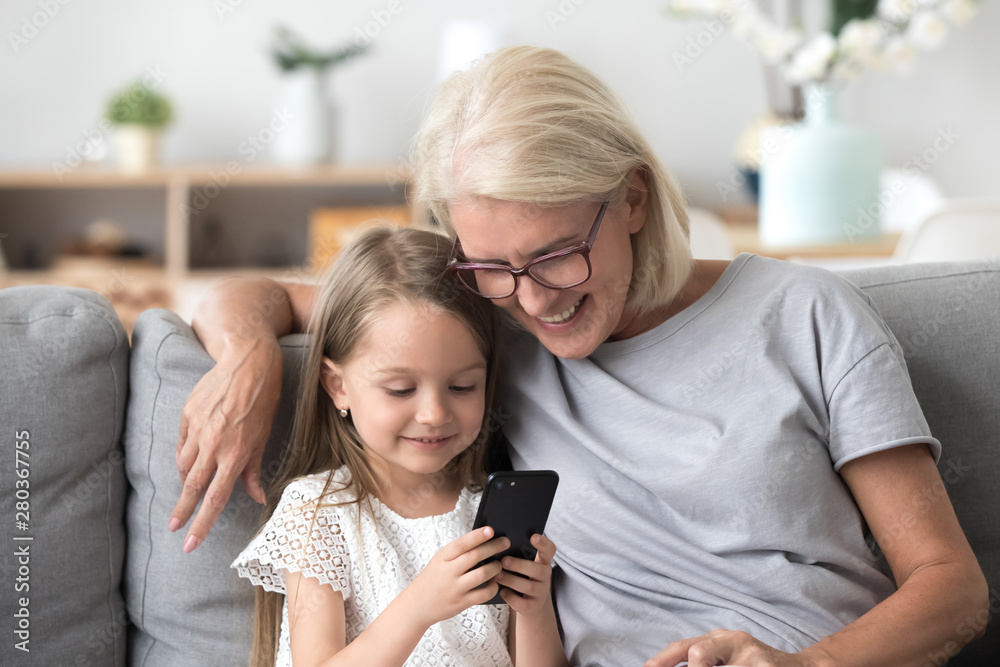 Grandma and grandchild using phone sitting on couch Grandma and grandchild using phone sitting on couch
