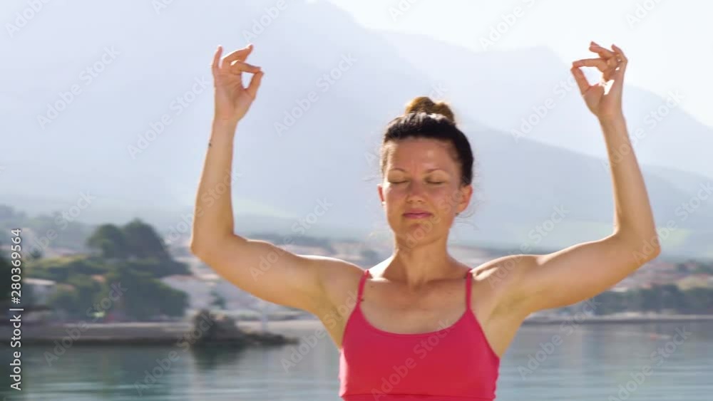 arc shot of adult woman closed her eyes practicing yoga at mediterranean seaside arc shot of adult woman closed her eyes practicing yoga at mediterranean seaside