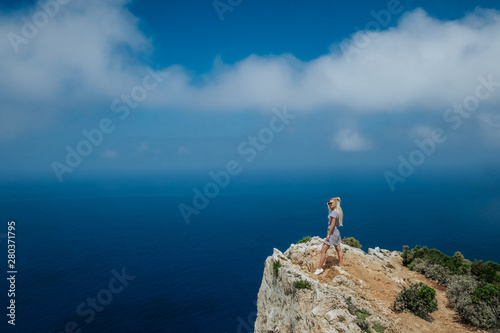 A young girl stands on the edge of a cliff.