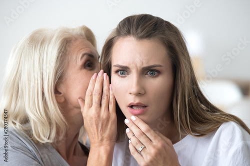 Close up portrait of mother and daughter whispering photo