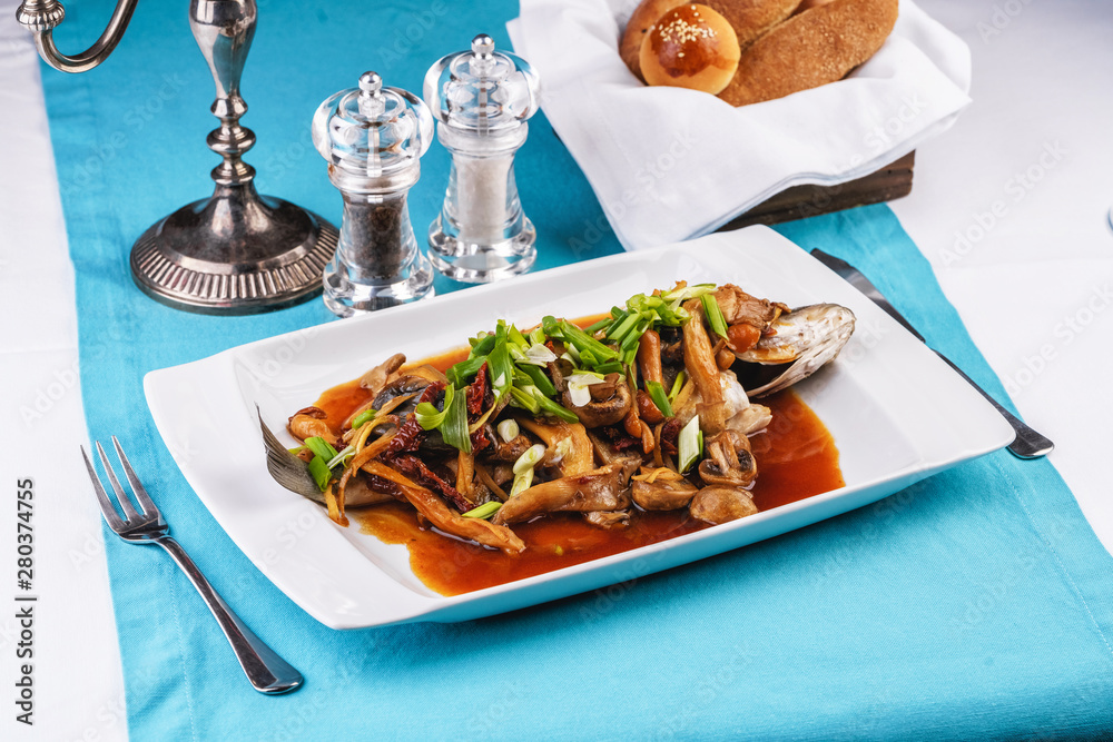 Seafood, Mediterranean cuisine, European dish. Fish stewed in tomato sauce with onion rings, mushrooms, herbs and vegetables. Caucasian national cuisine