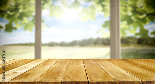 Table background and spring time. Green nature in blurred view in distance. Empty space for decoration and an advertising product.