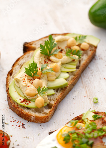Avocado sandwich with chickpea and herbs on a white table