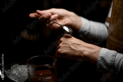 Close shot of bartender holding spoon for cocktails