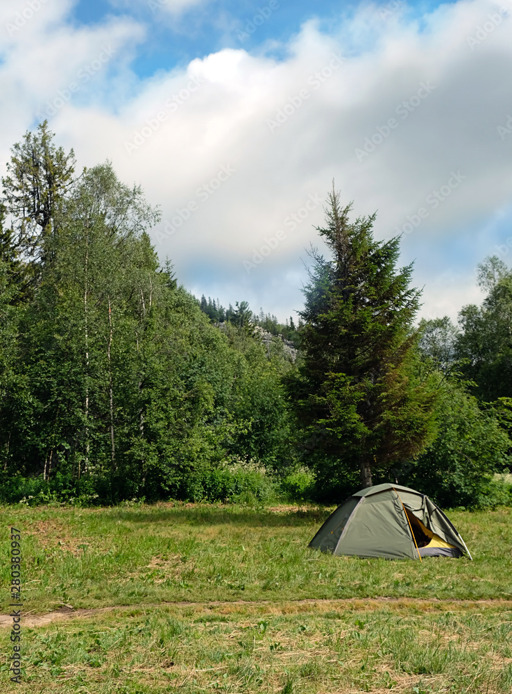 green tourist tent on meadow at campsite near mountain. concept of travel freedom, adventure, privacy. Camping place on nature in summer forest. Adventure travel active lifestyle outdoor background. 