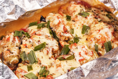 Seafood, Mediterranean cuisine, European dish. Fish baked in a foil with tomatoes, entirely with onion rings, red and green peppers, chili peppers, greens, cheese, mushrooms and vegetables. Caucasian 