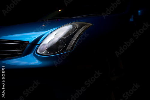  Headlight car. Headlight blue sports car. Part of the blue car on a dark background.