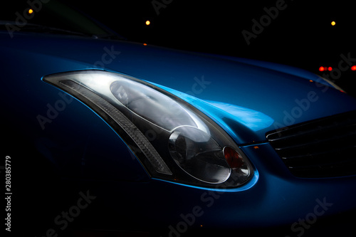  Headlight car. Headlight blue sports car. Part of the blue car on a dark background.