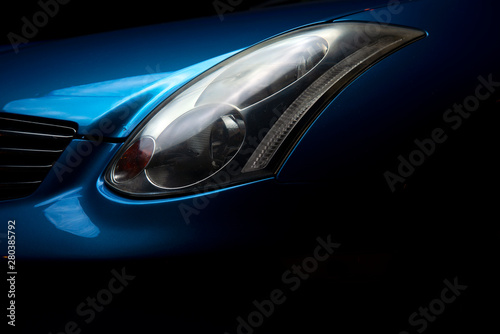  Headlight car. Headlight blue sports car. Part of the blue car on a dark background.