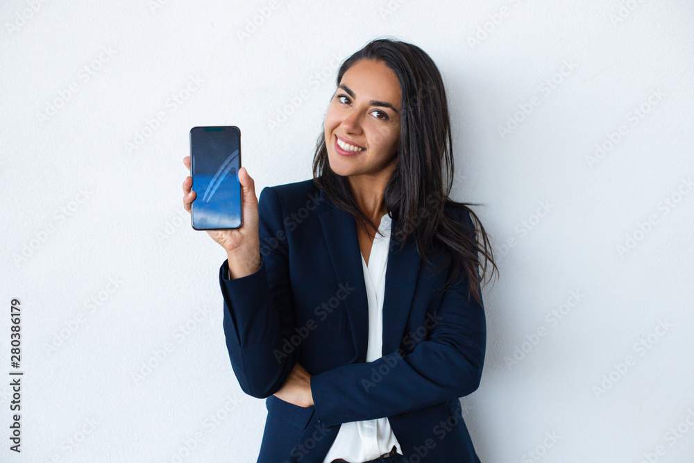 Happy young woman showing smartphone. Attractive cheerful young businesswoman holding cell phone and smiling at camera. Technology concept Happy young woman showing smartphone. Attractive cheerful young businesswoman holding cell phone and smiling at camera. Technology concept