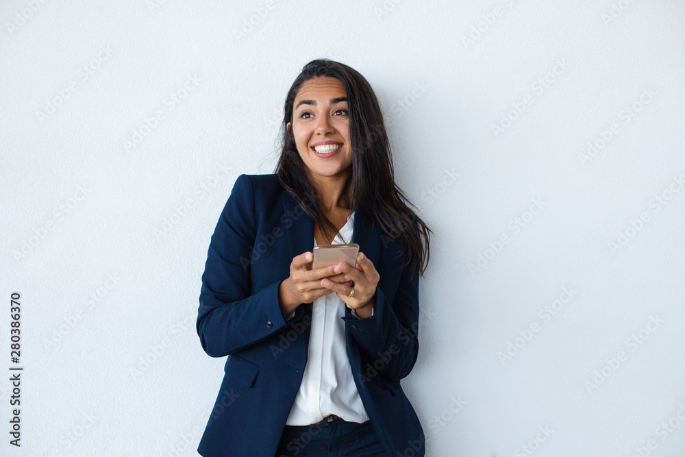 Cheerful businesswoman using mobile phone. Beautiful happy young businesswoman using smartphone isolated on grey background. Technology concept Cheerful businesswoman using mobile phone. Beautiful happy young businesswoman using smartphone isolated on grey background. Technology concept