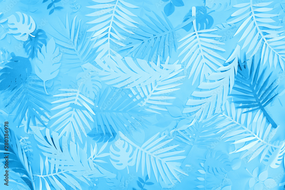 top view of exotic paper leaves on blue minimalistic background