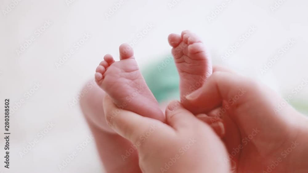 Children's legs in the hands of the mother. Tiny newborn baby feet on female hands closeup. Mother and child. The concept of a happy family. Children's legs in the hands of the mother. Tiny newborn baby feet on female hands closeup. Mother and child. The concept of a happy family.