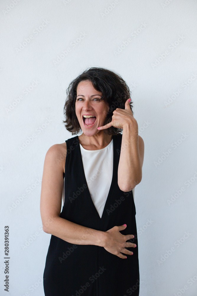 Excited woman asking for call. Happy middle aged woman showing call me symbol and smiling at camera isolated on grey background. Gesture concept Excited woman asking for call. Happy middle aged woman showing call me symbol and smiling at camera isolated on grey background. Gesture concept