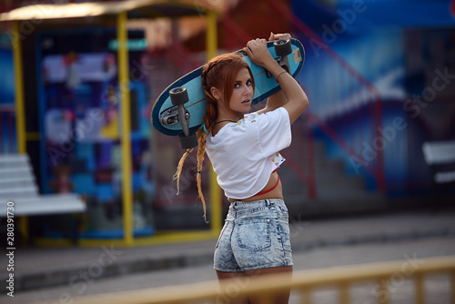 Girl holding skateboard in summer