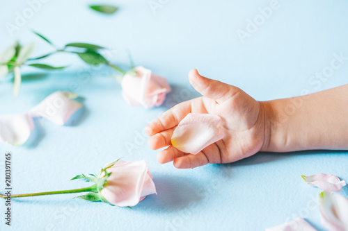 Fashion art  hand of a little child holding flowers on it blue  background