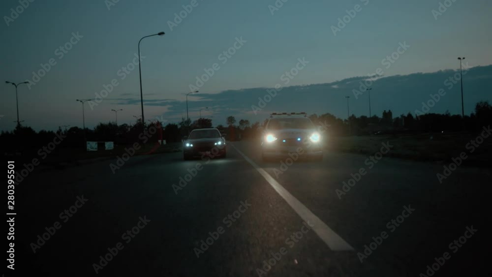 High speed police pursuit. Front view of a daring driver driving with police car behind in pursuit. Policemen chasing a drunk young man driving fast with his girlfriend. Night city. High speed police pursuit. Front view of a daring driver driving with police car behind in pursuit. Policemen chasing a drunk young man driving fast with his girlfriend. Night city.