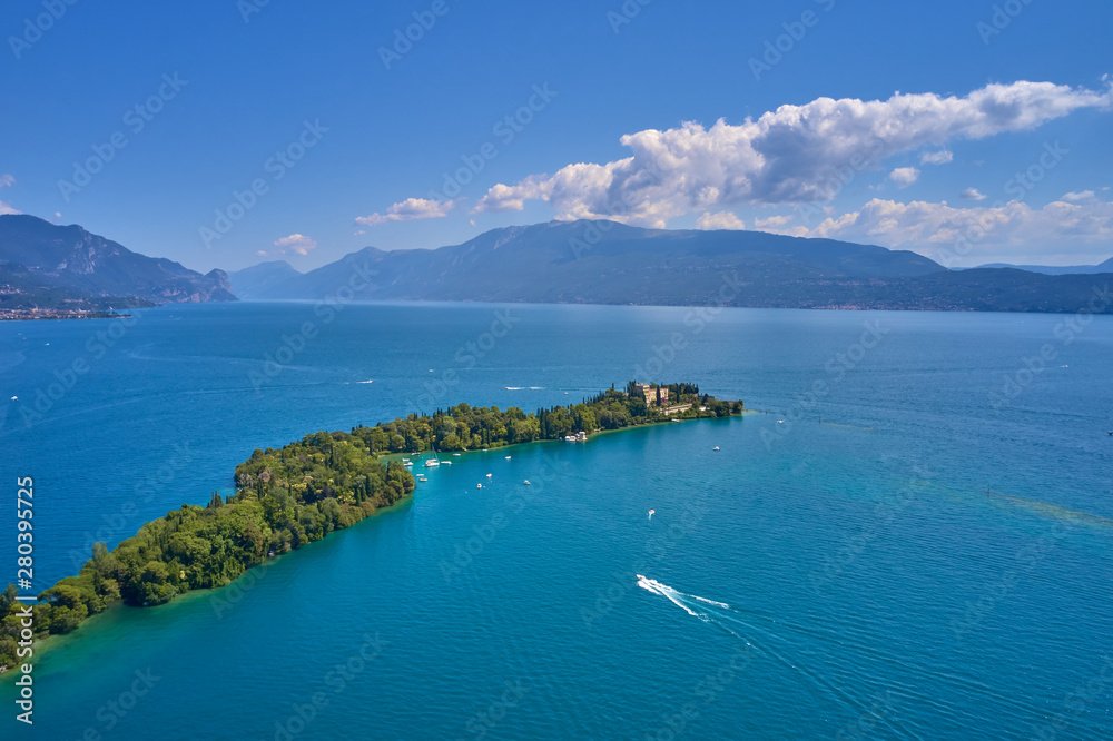 Unique view of the island of Garda. In the background is the Alps. Resort place on Lake Garda north of Italy. Aerial photography with drone.